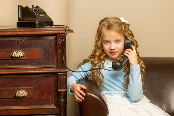 Malá holčička zvoní na starém telefonu. — Stock fotografie