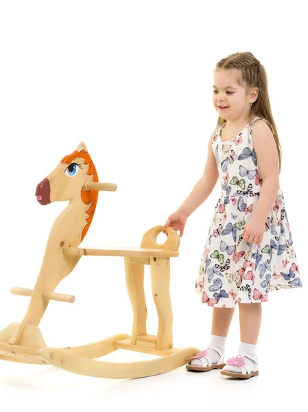 Girl swinging on a wooden horse. — Stock Photo, Image