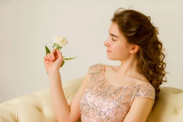 坐在沙发上的少女手里拿着一朵花. — 图库照片
