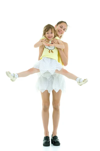 Schönes junges Mädchen hält ihre kleine Schwester auf dem Arm. — Stockfoto