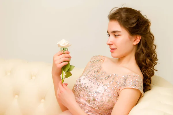 Teenie-Mädchen sitzt auf dem Sofa und hält eine Blume in der Hand. — Stockfoto