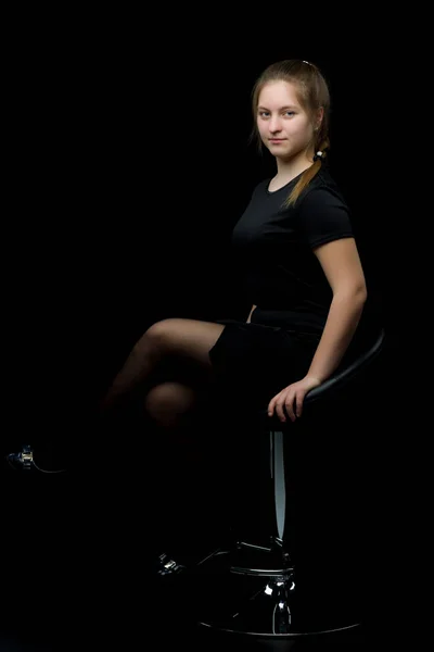 Bájos lány tinédzser ült egy széken a stúdióban egy bla — Stock Fotó