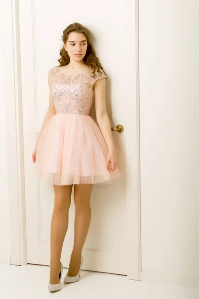 Menina adolescente em um vestido inteligente de pé perto da porta branca . — Fotografia de Stock