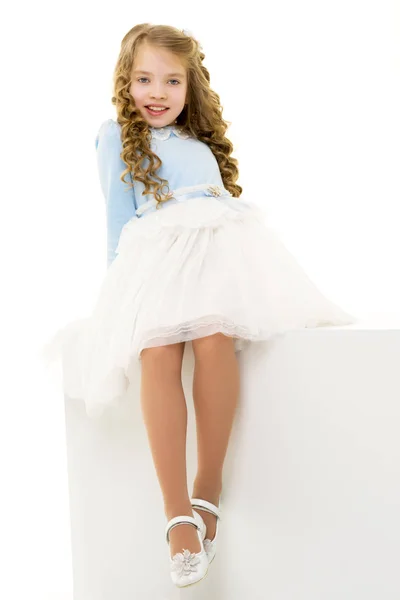 La bambina è seduta su uno striscione bianco. — Foto Stock