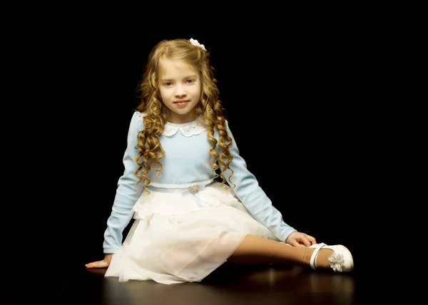En liten flicka sitter i studion på golvet på en svart b — Stockfoto