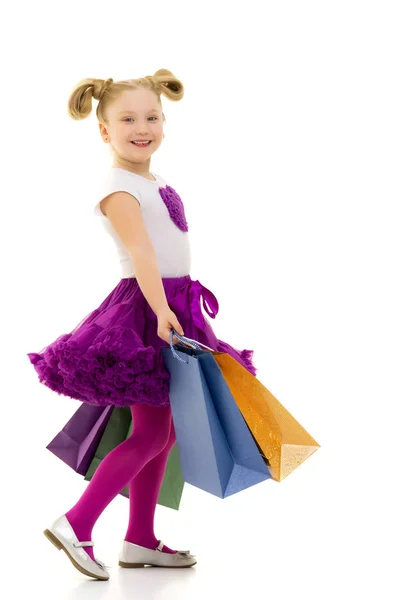 Petite fille avec des sacs multicolores dans leurs mains. — Photo