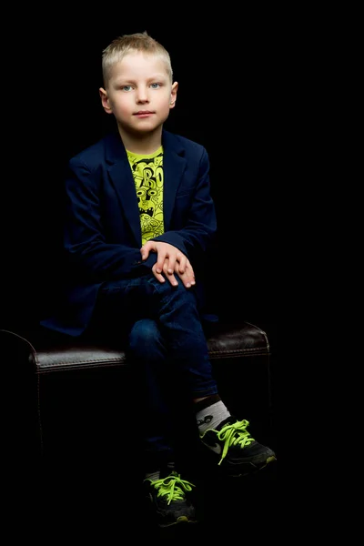 Liten pojke på en svart bakgrund. — Stockfoto