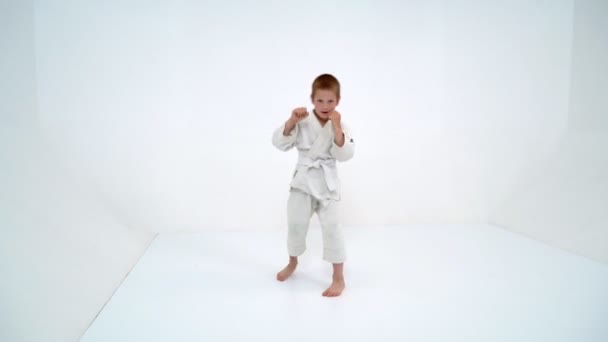 Un bambino in un kimono bianco compie colpi — Video Stock