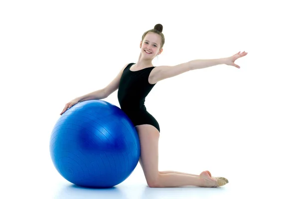 Liten flicka gör övningar på en stor boll för fitness. — Stockfoto