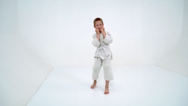 Een kleine jongen in een witte kimono vervult klappen — Stockvideo