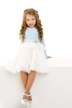 Küçük kız beyaz bir pankartta oturuyor..