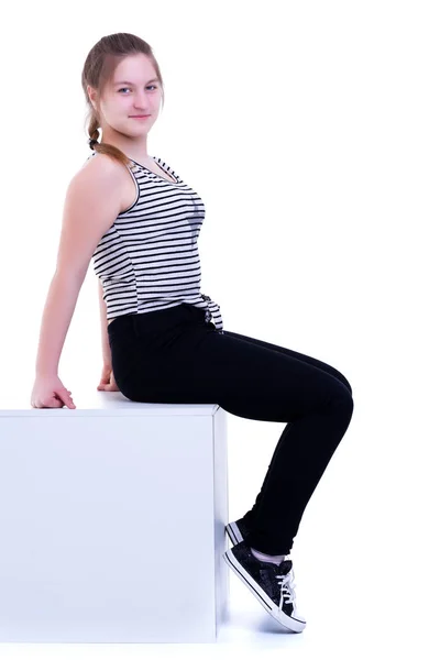 Teenage girl posing studio on a white cube. — Stock Photo, Image