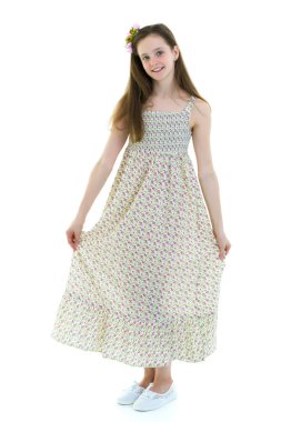 Güzel küçük bir kız rüzgârda duruyor, saçları ve kıyafetleriyle.