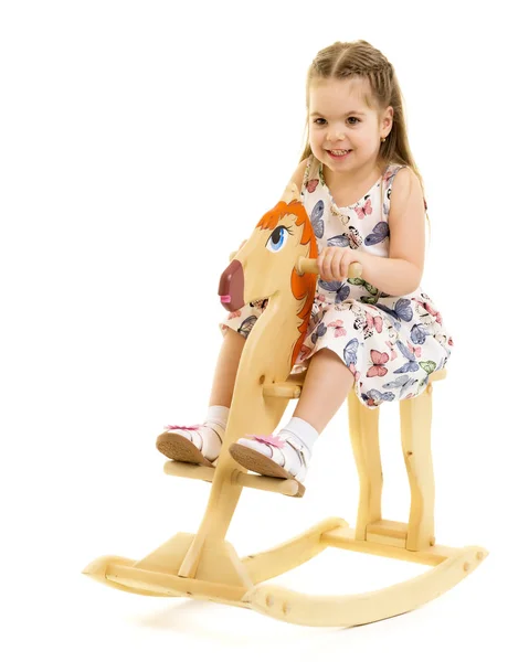 Menina balançando em um cavalo de madeira . — Fotografia de Stock