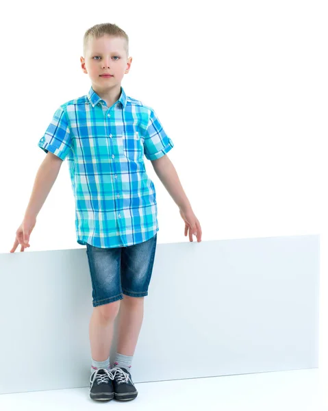 A little boy is looking from behind an empty banner. — Stock Photo, Image