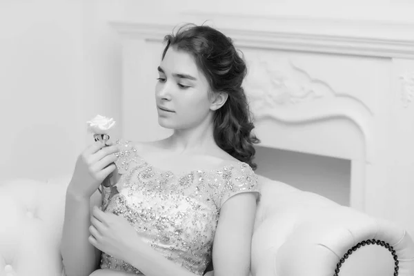 Adolescente sentada no sofá segurando uma flor na mão . — Fotografia de Stock