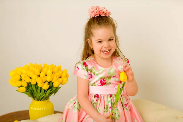 Klein meisje met een boeket tulpen. — Stockfoto