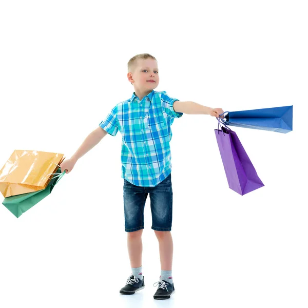 Niño pequeño agitando bolsas de papel multicolores. Va de compras. — Foto de Stock