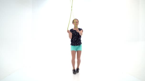 Een meisjesturnster doet oefeningen met een springtouw. — Stockvideo