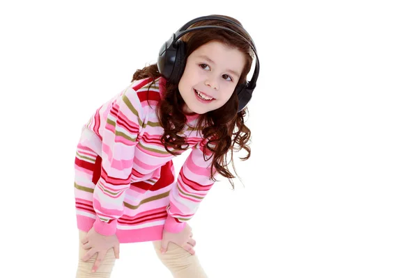 Una niña con auriculares escuchando música. — Foto de Stock