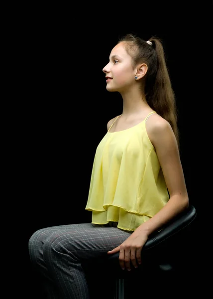 Bir genç kız bir deri sandalyede oturuyor. — Stok fotoğraf