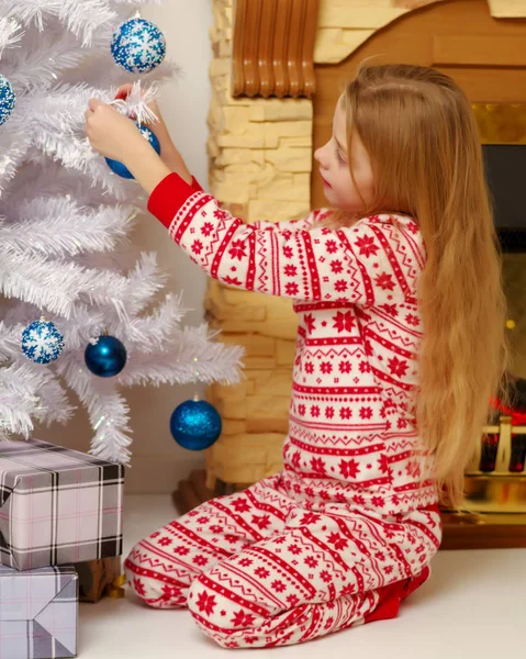 Une petite fille décore un sapin de Noël. — Photo