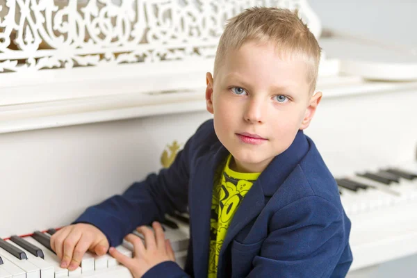 Liten pojke i studio nära vit piano. — Stockfoto