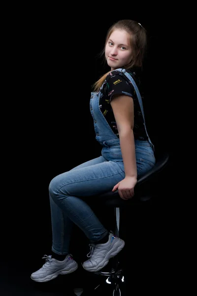 Charmant meisje tiener zittend op een stoel in de studio op een bla — Stockfoto
