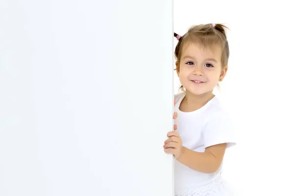 小さな女の子が空のバナーの後ろから見ている. — ストック写真