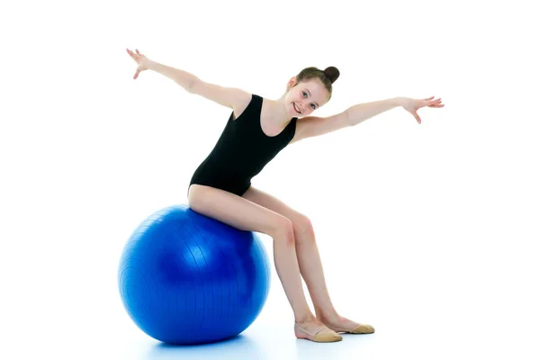 Маленькая девочка делает упражнения на большой мяч для фитнеса. — стоковое фото