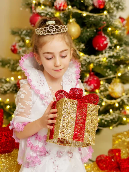 Menina perto da árvore de Natal com um presente. — Fotografia de Stock