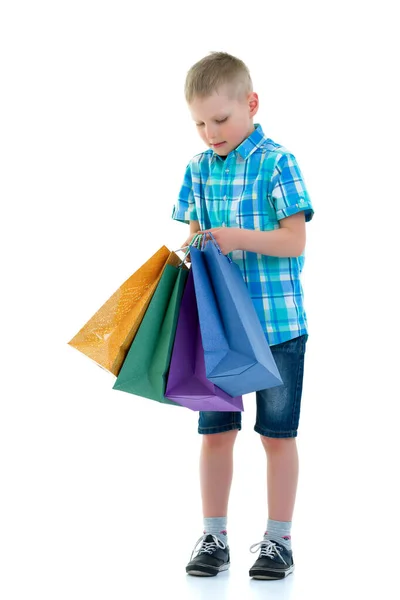 Liten pojke vifta mångfärgade papperspåsar. Han går och handlar — Stockfoto