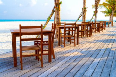 Tahta masa ve tropik ılık denizin yanındaki sandalyeler. Maldivler
