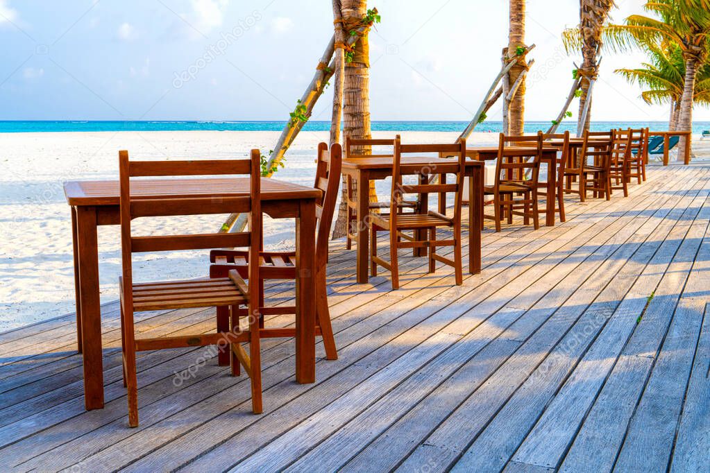 Wooden table and chairs by the tropical warm sea. Maldives