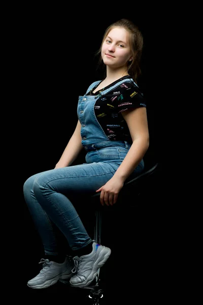 Чарівна дівчина підліток сидить на стільці в студії на блеку — стокове фото