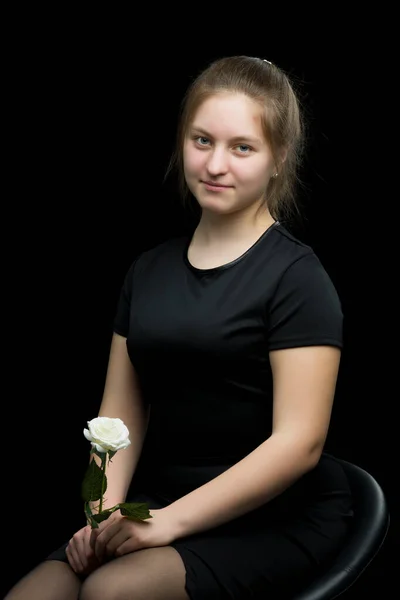 Bambina con un fiore bianco su sfondo nero . — Foto Stock