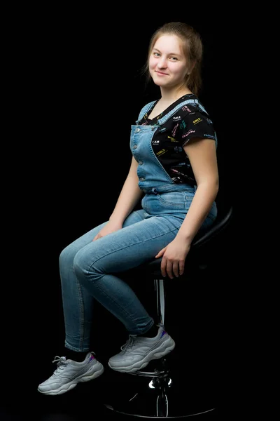 Okouzlující dívčí mladík, který sedí na židli ve studiu na bla — Stock fotografie