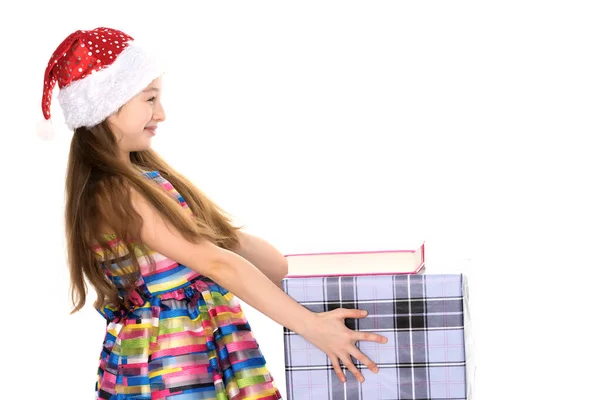 Ein kleines Mädchen mit einem Geschenk im Weihnachtsmann-Hut. — Stockfoto
