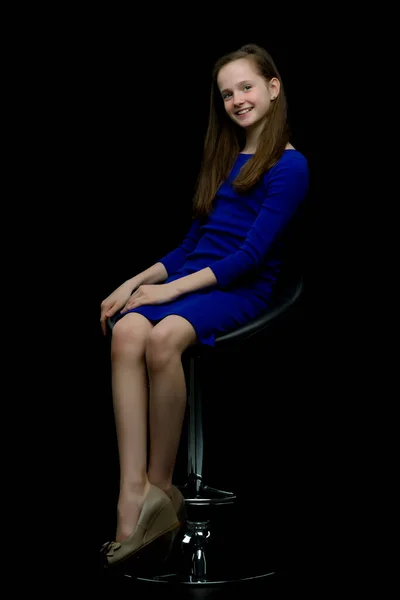 Affascinante ragazza adolescente seduta su una sedia in studio su una bla — Foto Stock