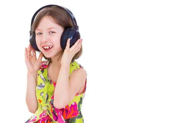 A little girl with headphones listening to music. — Stock Photo, Image