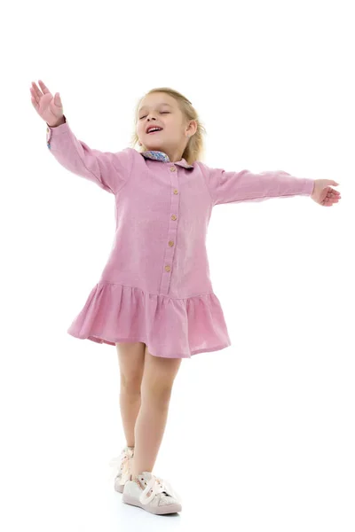 En liten flicka i klänning snurrar. — Stockfoto