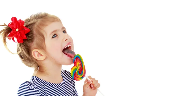 Mädchen leckt Bonbons an einem Stock. isoliert auf weißem Hintergrund. — Stockfoto