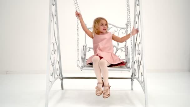 Happy little girl schoolgirl swinging on a swing. — Stock Video