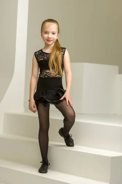 En liten flicka i dansdräkt sitter på trappan.. — Stockfoto