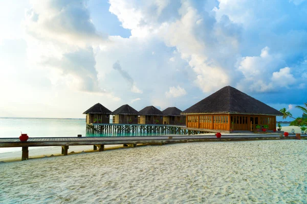 Puentes de madera que conducen a las cabañas a orillas del mar tropical y cálido. Maldivas. Concepto turístico. — Foto de Stock