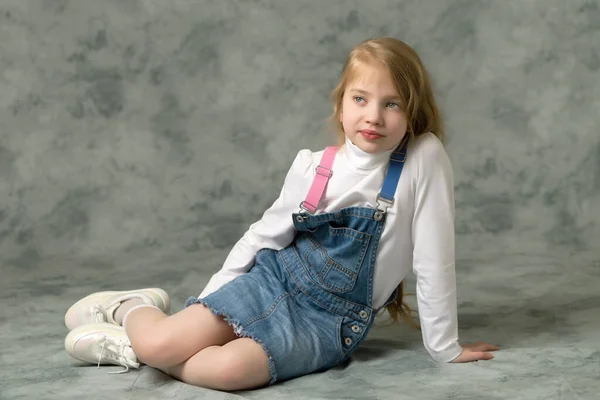 Klein meisje in een korte denim jurk. — Stockfoto