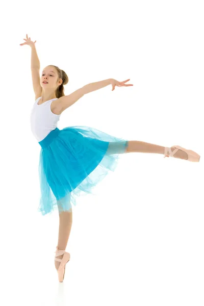 Schattig klein meisje in een tutu en pointe schoenen dansen in de studio op een witte achtergrond. — Stockfoto