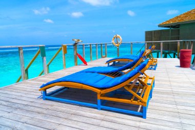 Maldivler 'de güzel bir tropik plajda şezlonglar.