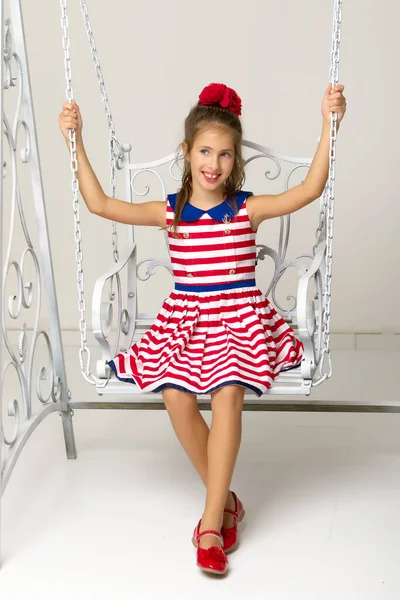 Happy little girl schoolgirl swinging on a swing. — Stock Photo, Image