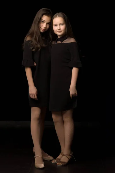 Dvě malé holčičky pózující ve studiu na černém pozadí. Sty — Stock fotografie